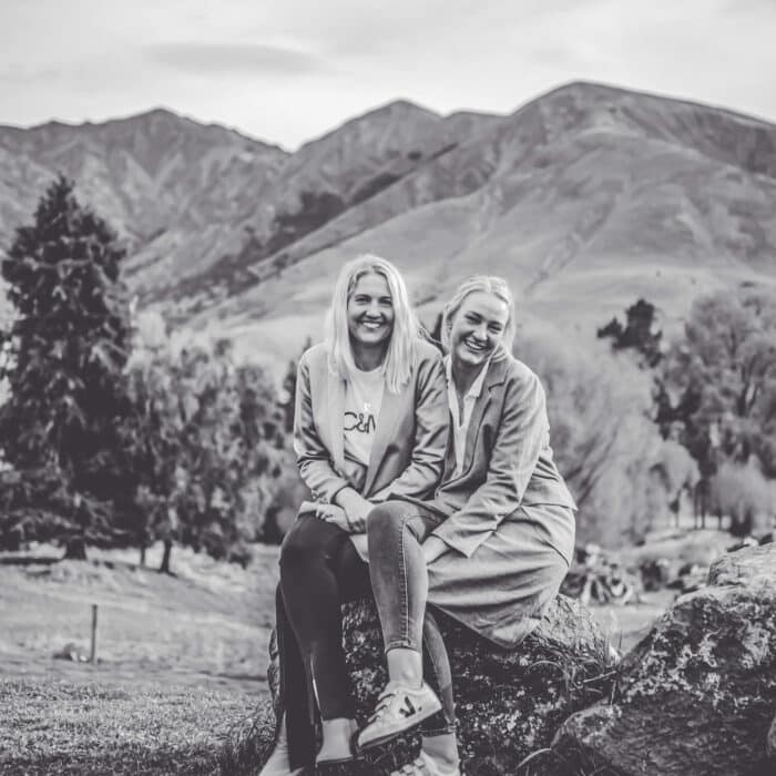 Black and white photo of two sisters sitting on a rock