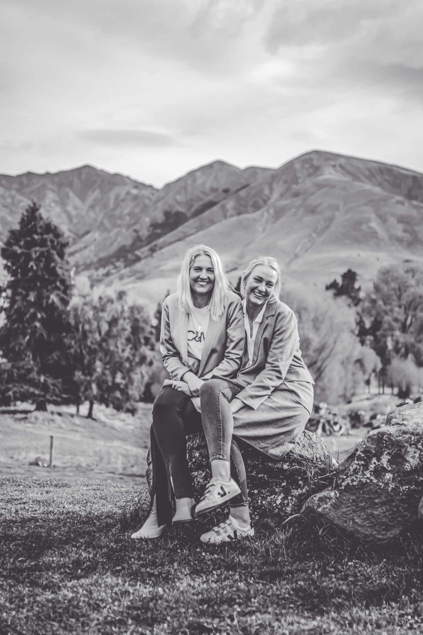 Black and white photo of two sisters sitting on a rock