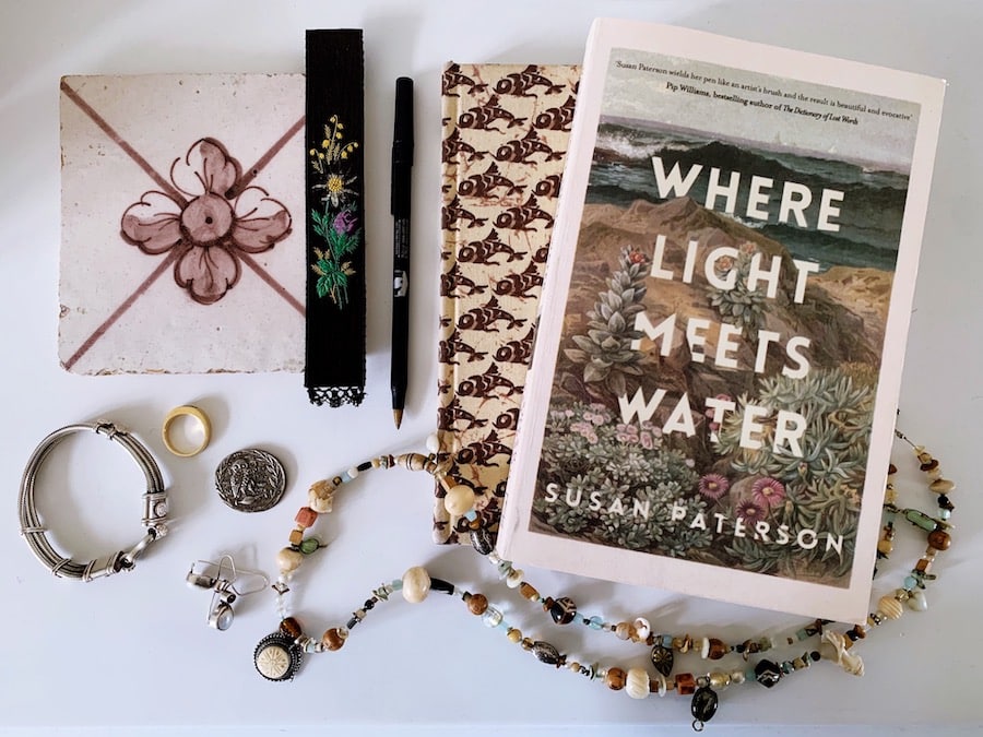 Books, jewellery and miscellaneous bedside table items laid out.