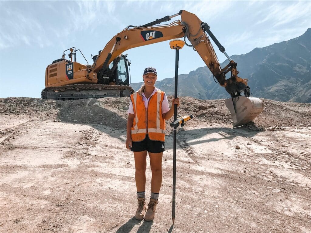 Olivia Thomson standing in front of a digger