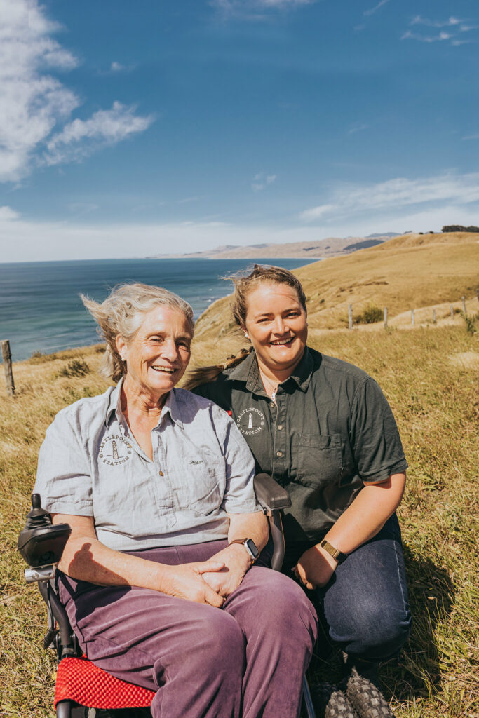 Emily and Sarah Crawfoot sit in front of the ocean