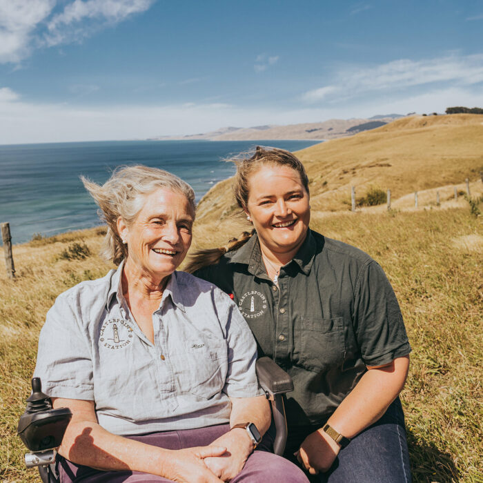 Emily and Sarah Crawfoot sit in front of the ocean