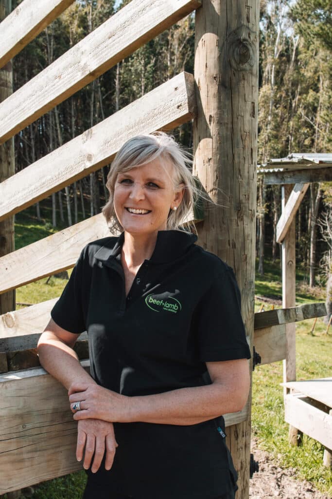 A woman stands against a livestock loading ramp.