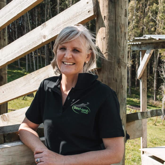 A woman stands against a livestock loading ramp.