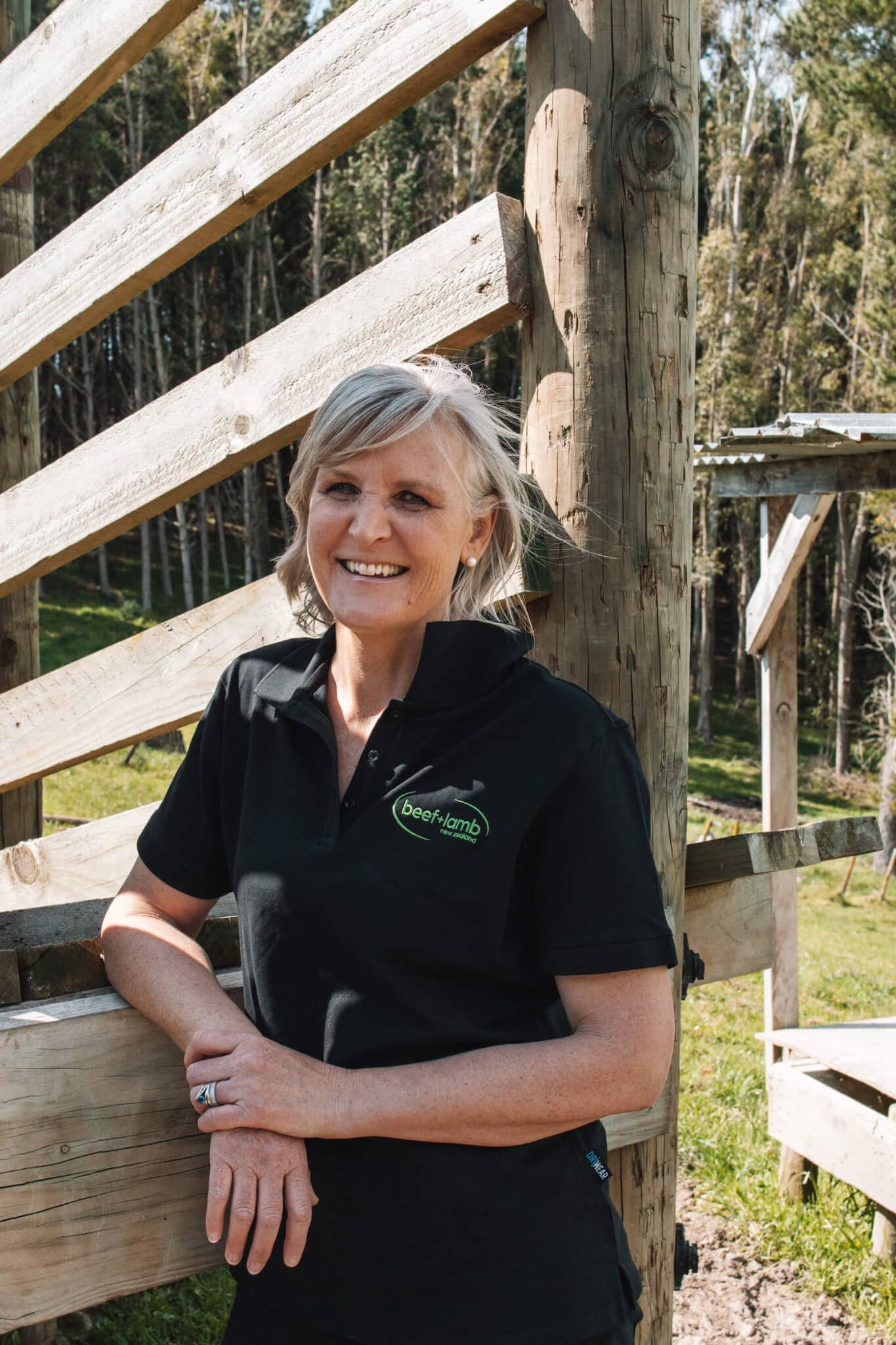 A woman stands against a livestock loading ramp.